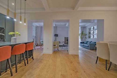 Apartamento moderno en Madrid con cocina abierta, comedor con sillas naranjas y salón con sofá azul