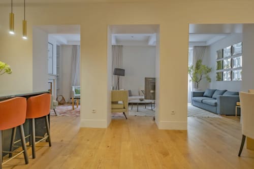 Apartamento moderno en Madrid con salón diáfano, suelos de madera, columnas blancas y mobiliario contemporáneo