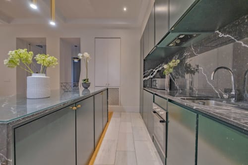 Cocina moderna en Apartamentos Andimi Madrid con revestimiento de mármol negro, gabinetes blancos y elegantes arreglos florales