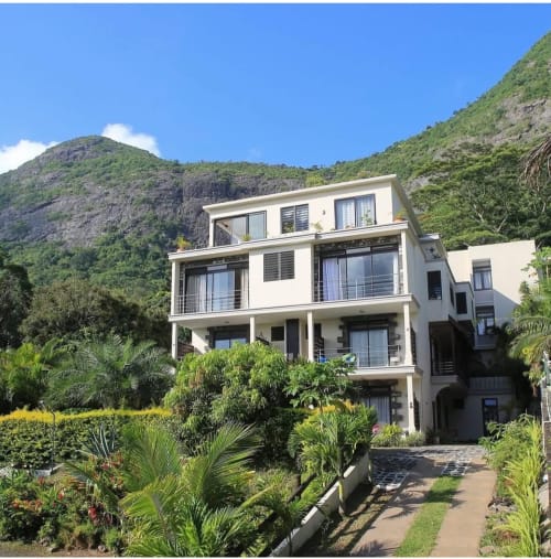 Modern white apartment building with mountain view at Joubarbe Résidence in Moka, surrounded by tropical gardens and lush