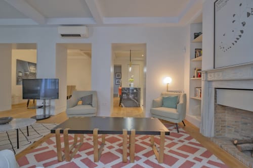 Sala de estar de apartamento moderno en Madrid con mesa de comedor, área de estar, televisor, chimenea y planta abierta