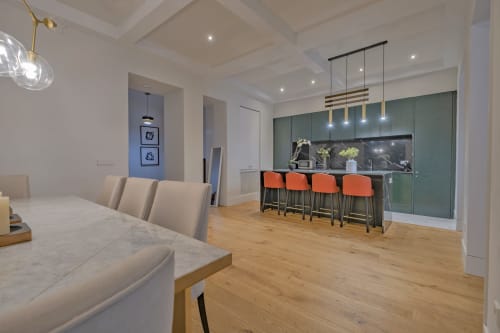 Comedor y cocina de apartamento moderno en Madrid con taburetes naranjas, suelos de madera y vistas a la ciudad