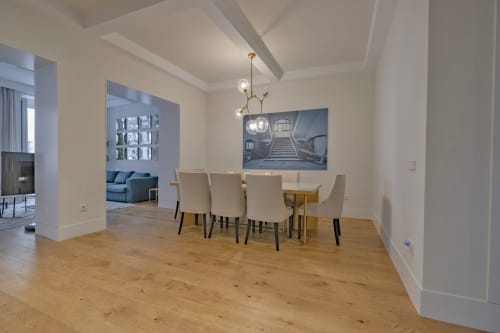 Comedor moderno con mesa de madera, sillas crema y lámpara colgante contemporánea en apartamento de Madrid