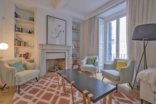 Sala de estar moderna de apartamento madrileño con chimenea, vistas a la ciudad, asientos cómodos y alfombra geométrica
