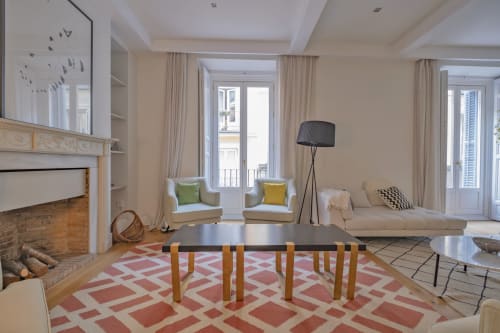 Sala de estar de apartamento moderno en Madrid con chimenea, balcón con vistas a la ciudad, alfombra geométrica y muebles contemporáneos