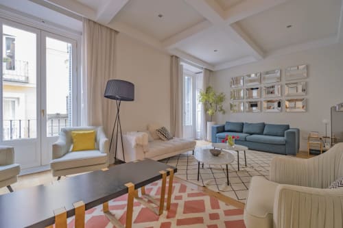 Moderno salón de apartamento en Madrid con cómodos asientos, sofá azul, vistas a la ciudad y acceso a balcón en Andimi Apartaments
