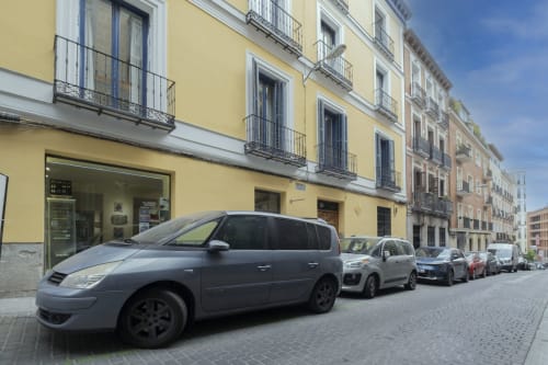 Vista callejera de Andimi Apartamentos en Madrid con coches aparcados y edificios históricos amarillos con balcones