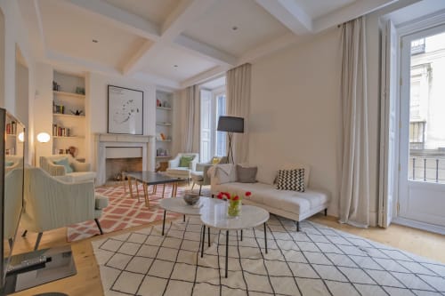 Amplio salón con chimenea en apartamento madrileño, vistas a la ciudad, mobiliario moderno y acceso a balcón