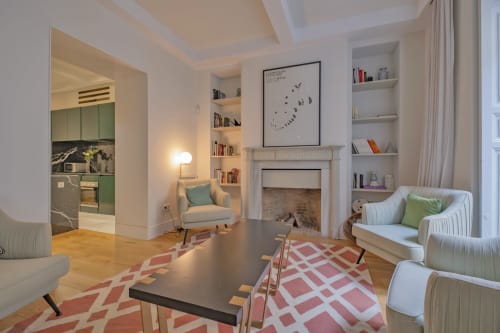 Sala de estar de apartamento moderno en Madrid con chimenea, estanterías integradas, asientos confortables y alfombra con patrón geométrico