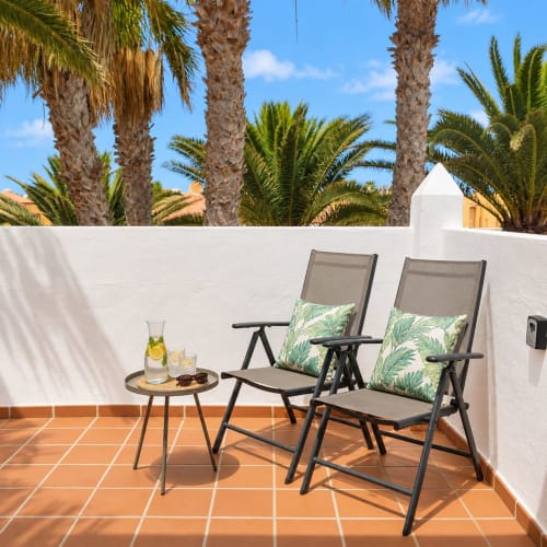 Terrasse mit Liegestühlen und Getränken in Sara & Gino Fuerteventura, Corralejo, umgeben von Palmen und weißen Mauern