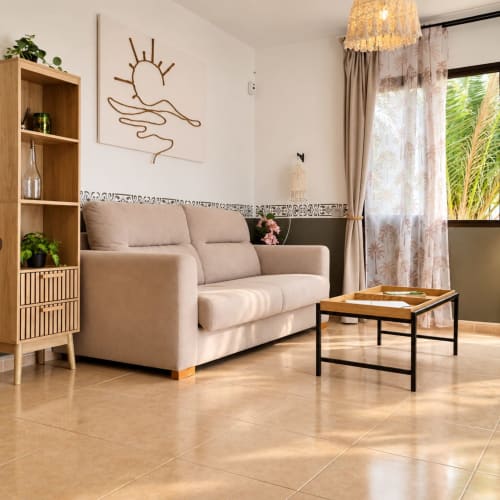 Modernes Wohnzimmer mit beigem Sofa, Holzregalen und Terrakotta-Fliesenböden in der Wohnung Sara & Gino auf Fuerteventura,