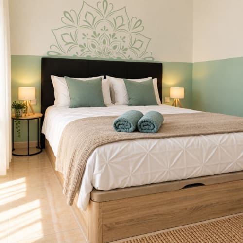 Luxuszimmer Sara & Gino Fuerteventura mit grüner Akzentwand, Mandala-Kopfteil, gerollten Handtüchern und Nachttischlampen