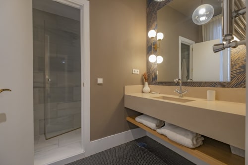 Moderno baño en Andimi Apartments Madrid con lavabo, iluminación de espejo y ducha a ras de suelo