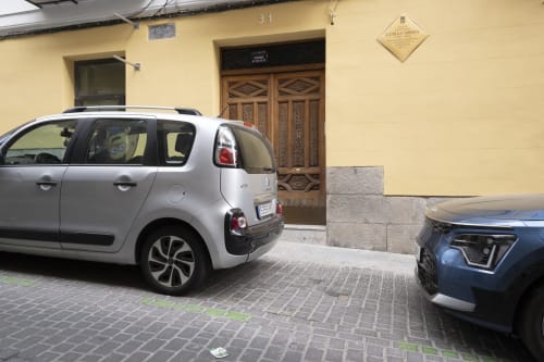 Citroën C1 blanco estacionado en una calle de Madrid frente a un edificio amarillo con puertas de madera ornamentadas