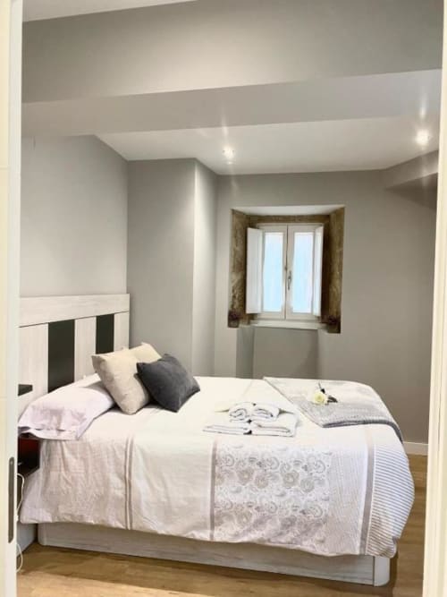 Dormitorio de cama queen en el hotel A Casiña D'Avoa en Osera con ropa de cama blanca, cabecero a rayas y ventana con cortinas marrones