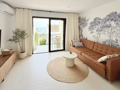 Bright coastal townhouse living room with terracotta sofa, sea view balcony, and botanical wall art in Calahonda