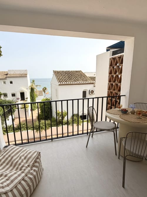 Seaside balcony with sea view, dining table, chairs, and striped lounger at Marbella beachfront townhouse