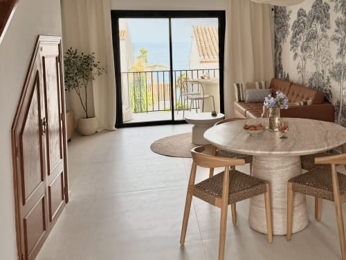 Modern sea-view townhouse living area with dining table, brown sofa, and balcony overlooking Calahonda beach, HomyMarbella