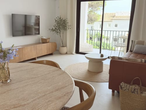 Bright living room with wooden dining table, modern furnishings, TV, and balcony overlooking Calahonda at HomyMarbella