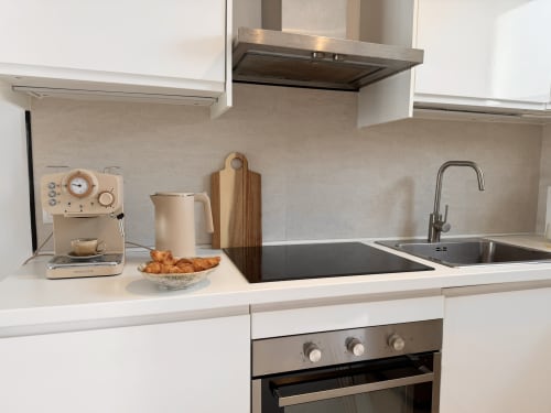 Modern kitchen in Calahonda cottage with white cabinetry, stainless steel appliances, and beige backsplash