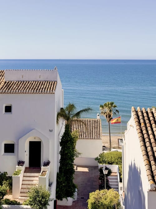 White Mediterranean townhouse with terracotta roof overlooking beach in Calahonda, Marbella with sea view and palm trees
