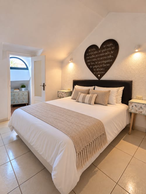 Modern bedroom in Manage Home Tenerife duplex with queen bed, black heart wall art, and city views from balcony