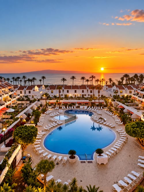 Sunset view of Manage Home Tenerife resort with poolside loungers, palm trees, and ocean backdrop in Spain