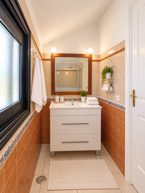 Modern bathroom in Duplex Agnes Parque Santiago I, Tenerife with terracotta tiles, white vanity, and decorative accents