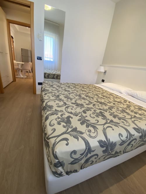 Camera confortevole della Residence Aida a Rimini con letto matrimoniale decorato, pavimentazione in legno e moderni servizi