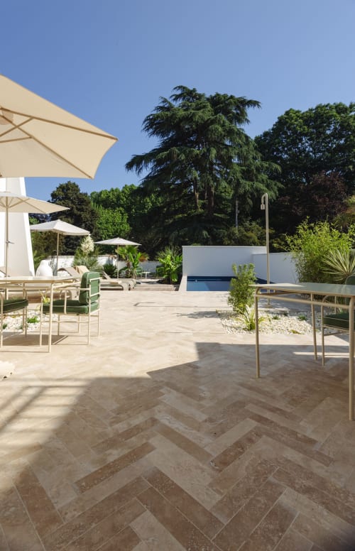 Terrasse moderne au bord de la piscine de L'Ode à Pierre à Dax avec transats, parasols et jardins entretenus