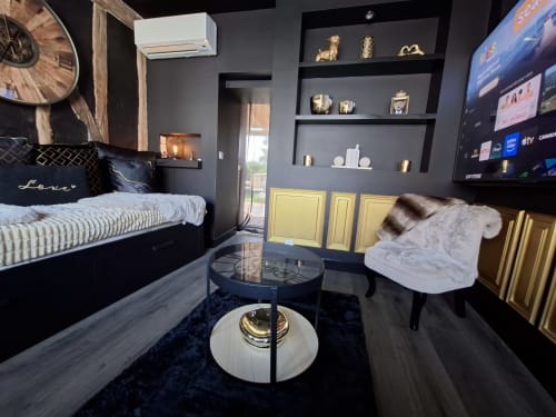 Chambre moderne et romantique à Esches avec lit noir, dorures, TV écran plat et coin salon