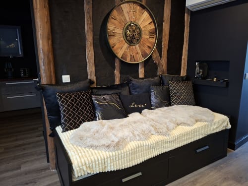 Chambre de cottage luxueuse avec lit noir, coussins décorés, literie crème, poutres en bois et grande horloge murale à Love Room