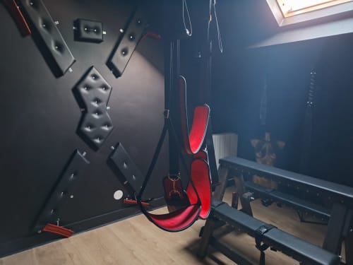 Chambre moderne avec chaise gaming rouge, murs sombres et espace divertissement à l'hôtel Love Room Sensation à Esches,