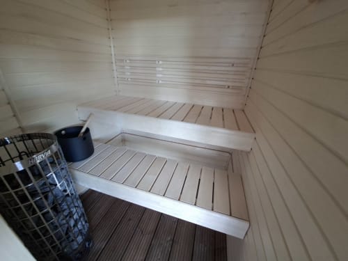 Intérieur du sauna du cottage Love Room Sensation à Esches avec bancs en bois et seau