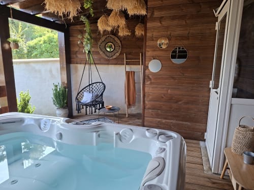 Chambre de luxe avec baignoire jacuzzi remplie, fauteuil suspendu, décor bois et vue sur jardin à Love Room Sensation à Esches,