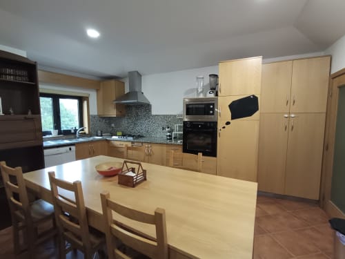 Cozinha moderna na Casa da Avó de Quinta d'Areda com armários de madeira, mesa de refeições e eletrodomésticos em aço inoxidável em Fafe,