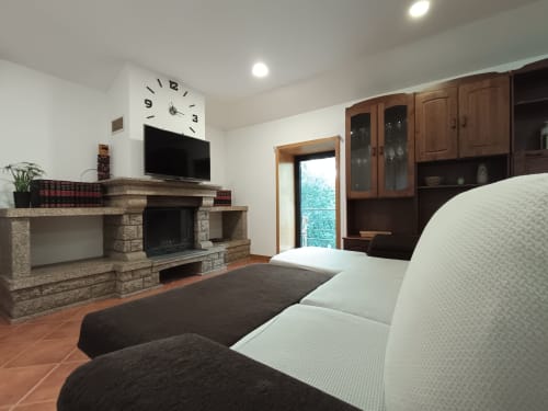 Quarto aconchegante da Quinta d'Areda com camas individuais, lareira de pedra, TV e portas com vista para o lago em Fafe
