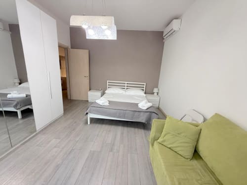 Camera da letto dell'appartamento Deledda a Firenze con divano letto, mobili bianchi e servizi moderni