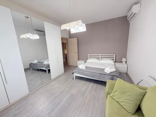 Camera moderna dell'appartamento Deledda a Scandicci con letti gemelli, armadio a specchio, divano e vista sulla città