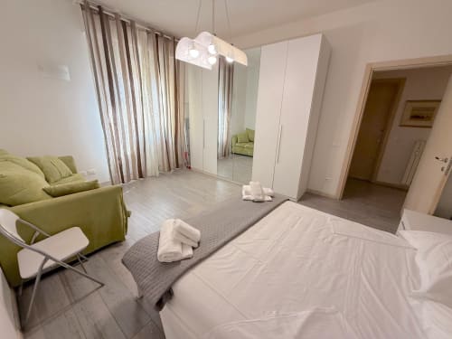 Camera moderna dell'appartamento Florence Sweet Homes Deledda a Scandicci con divano, letto bianco, armadio e vista sulla città