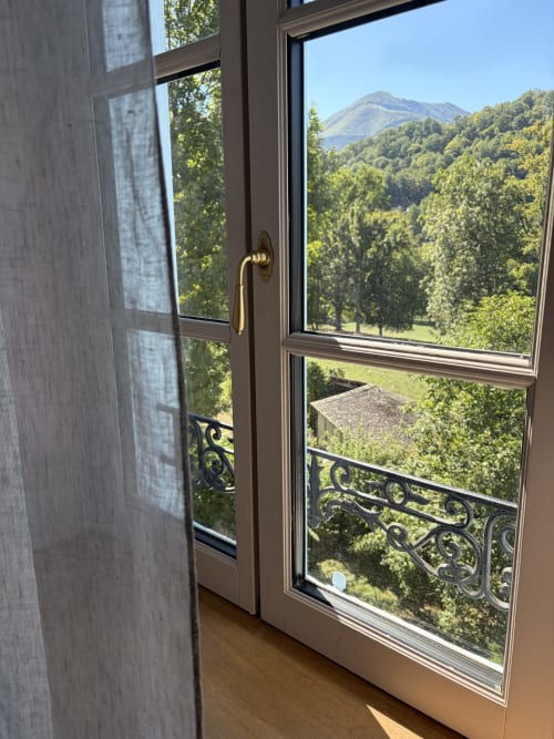 Portes-fenêtres ouvertes de la Maison Crone offrant une vue sur les jardins luxuriants et les montagnes de Castillon-en-Couserans
