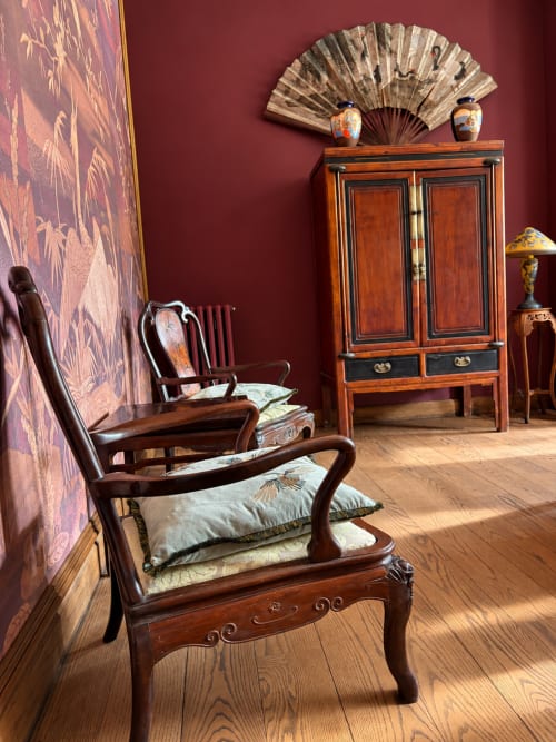 Suite asiatique élégante à Maison Crone : mobilier en bois, murs bordeaux, éventails décoratifs
