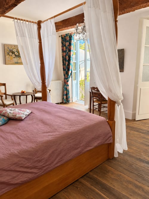 Lit à baldaquin élégant avec draps roses à la Chambre Eva de Maison Crone, Castillon-en-Couserans, portes sur jardin et blanc