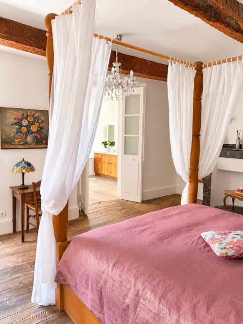 Lit à baldaquin élégant avec linge rose et rideaux blancs à la Maison Crone B&B à Castillon-en-Couserans, France