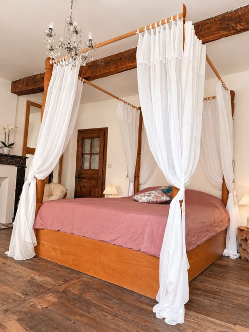 Lit à baldaquin en bois avec voilages blancs et parure rose dans la Chambre Eva de la Maison Crone, Castillon-en-Couserans