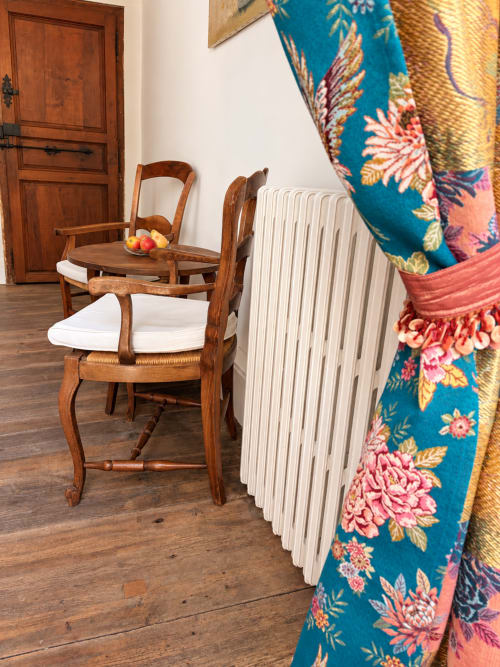 Chaise en bois avec coussin blanc et rideaux fleuris colorés dans la Chambre Eva de la Maison Crone, Castillon-en-Couserans