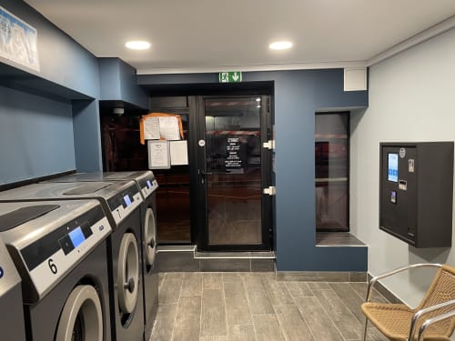 Buanderie moderne de l'hôtel Le Celtic au Thillay avec lave-linge industriels et espace détente