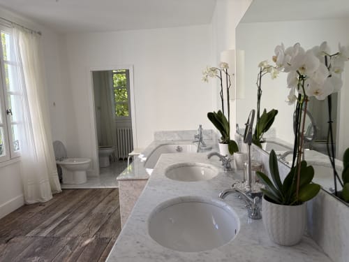 Salle de bain luxueuse à Maison Crone avec vasques jumelées, orchidées blanches et vue sur le jardin à Castillon-en-Couserans