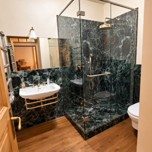 Salle de bain luxueuse à la Maison Crone BnB avec murs en marbre noir, pomme de douche pluie et équipements modernes