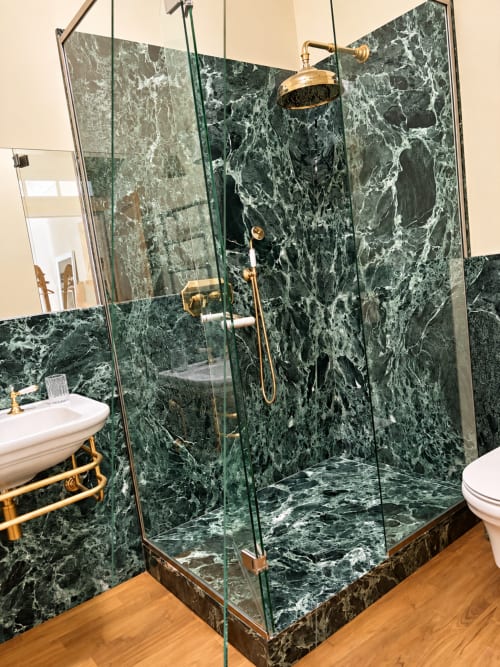 Salle de bain luxueuse Maison Crone avec douche en marbre vert foncé, luminaires en laiton et revêtement de sol en bois